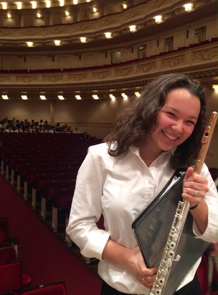Gabriela Beltrán smiling with her flute in an ornate concert hall before a Carnegie Hall performance