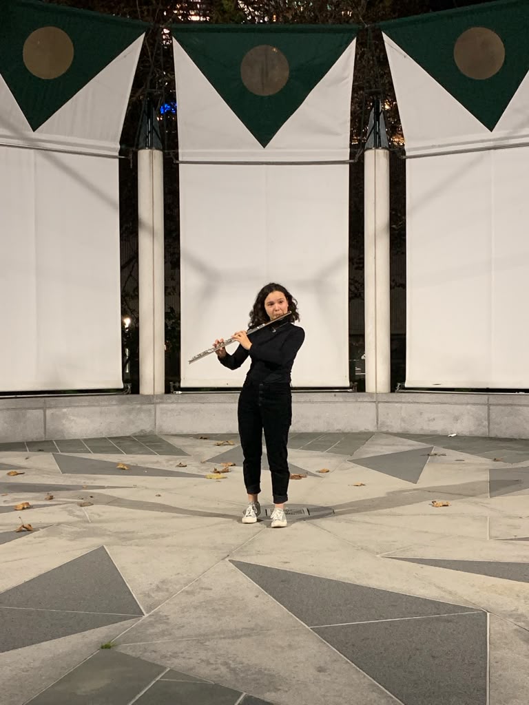 Gabriela Beltrán playing flute in an outdoor pavilion at dusk