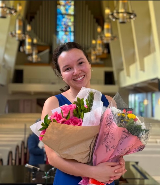 Portrait of Gabriela Beltrán holding flowers in a concert hall
