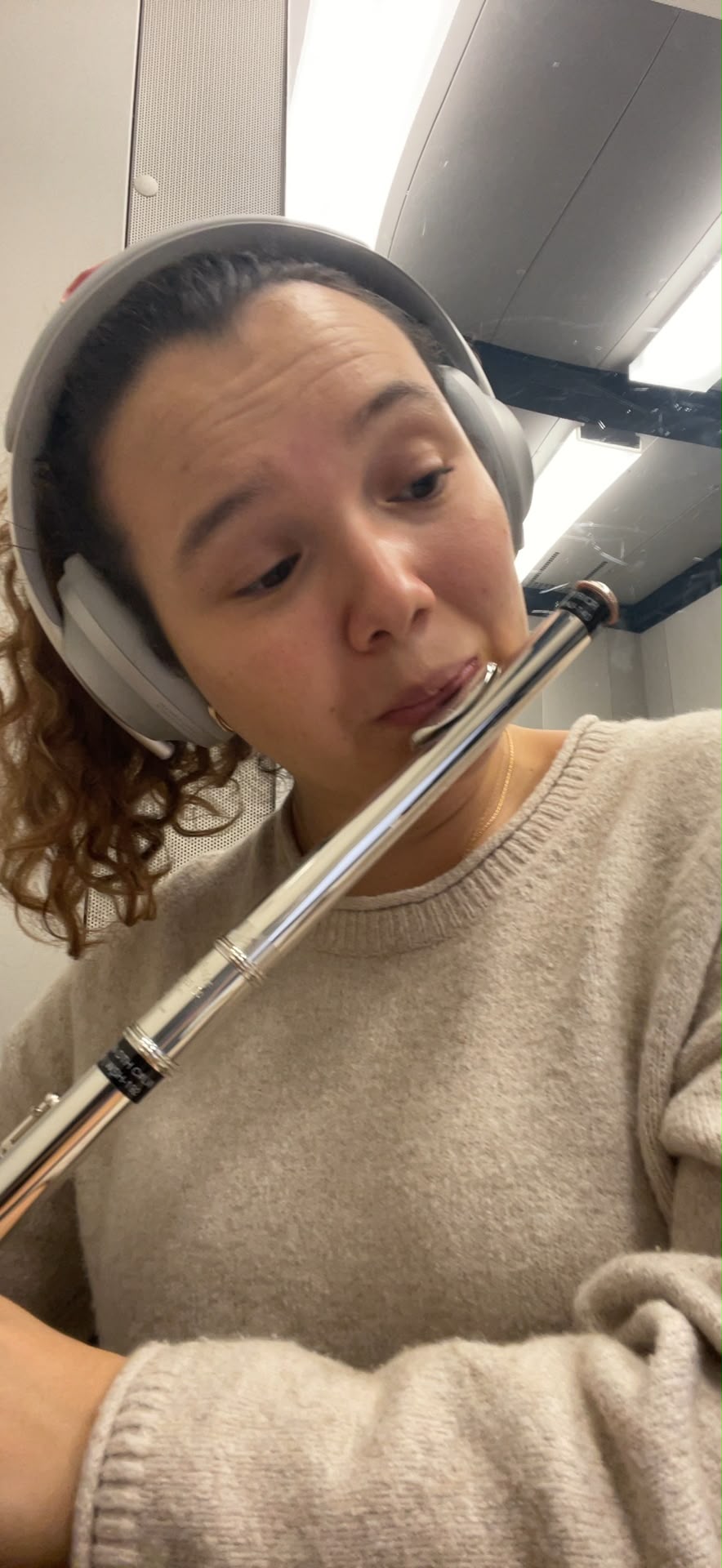 Close portrait of Gabriela Beltrán playing flute while wearing studio headphones